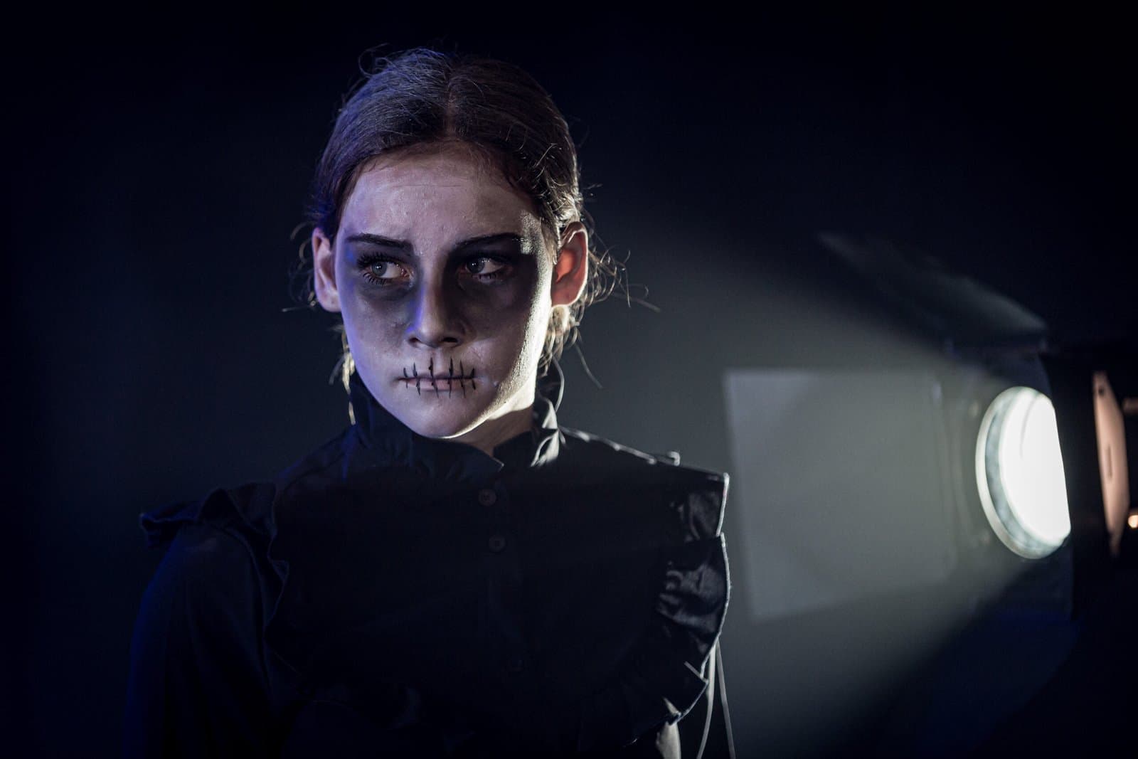 Performer in skull makeup lit by a stage lantern.